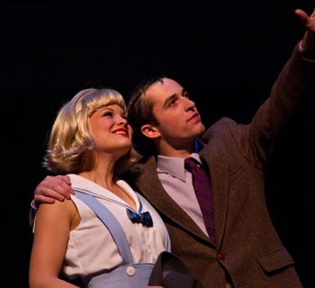 A man pointing high while holding a blonde woman’s shoulder
