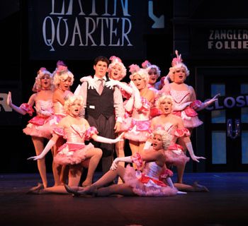 A man surrounded by female dancers in pink of Crazy for You the Musical