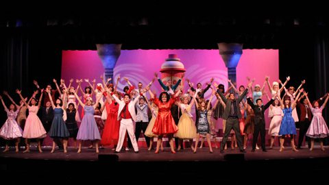 Hairspray ensemble with all their arms up