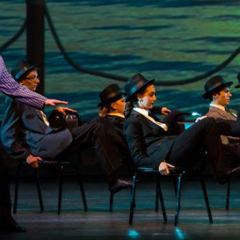 A group of performers sitting on chairs with their feet up