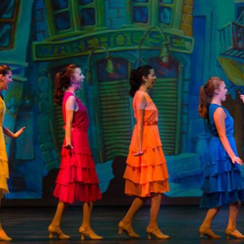 Four girls wearing blue, orange, red, and yellow dresses