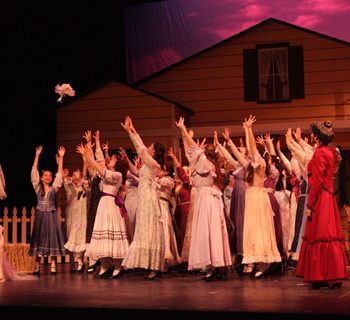 A group of girls in dresses on a stage.