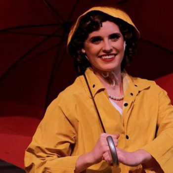 A woman in a yellow raincoat holding a red umbrella