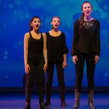 Three young girls wearing black while singing