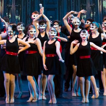Performers wearing black dresses and masks