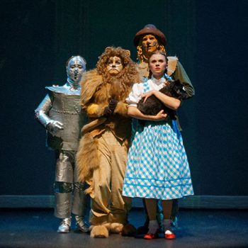Dorothy, the Cowardly Lion, the Scarecrow, and the Tin Man huddling together