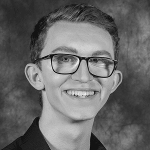 A black and white photo of a young man wearing glasses.