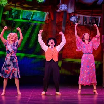 Three characters from Annie with their arms up