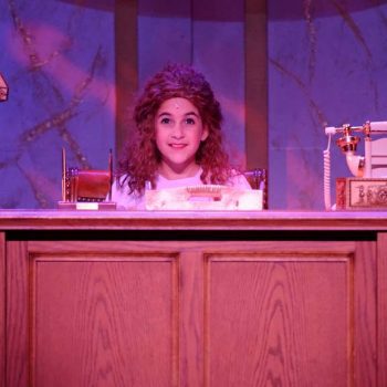 A young girl behind a desk in Annie