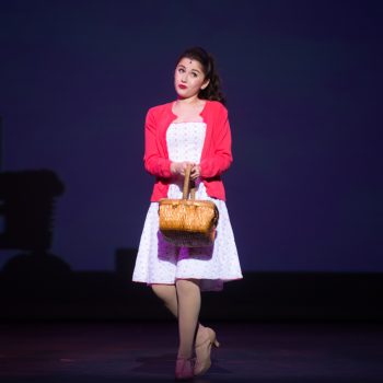 A young woman wearing a white dress and a red cardigan while holding as basket
