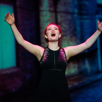 A theatre actress singing a high note