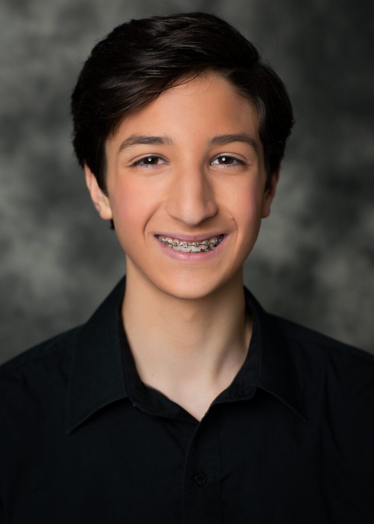 A young man wearing a black shirt and braces.