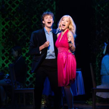 Musical theatre actors singing on stage.