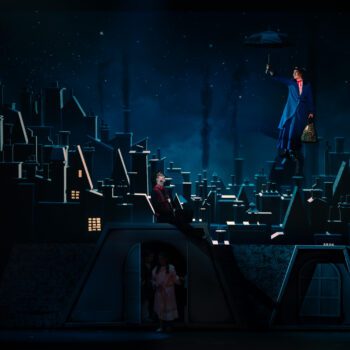 Person flying with umbrella over nighttime rooftops