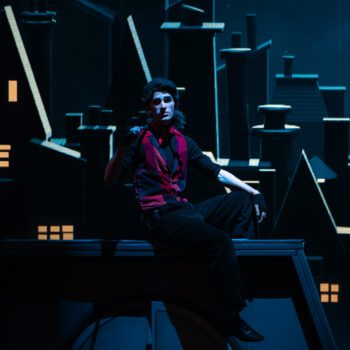 Performer on theatrical rooftop set at night