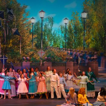 Ensemble cast performing in park with kites