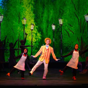 Lead dancer in striped blazer and straw hat