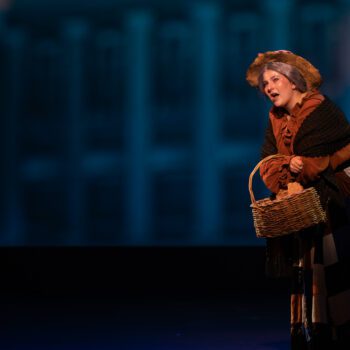 Stage actress in period costume singing with basket