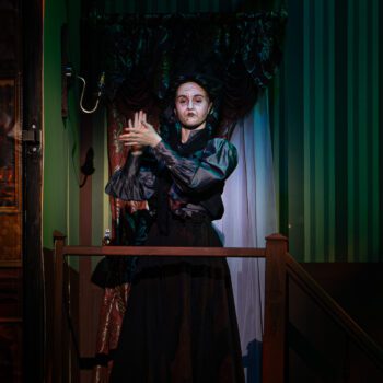 Theatrical person in Victorian costume on staircase