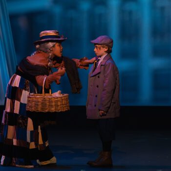 Actors in period costumes on stage exchanging basket