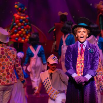 Actor in purple coat on colorful musical stage