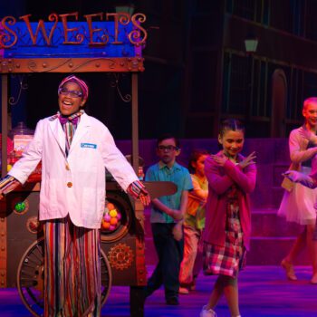Smiling vendor performer at colorful sweets cart