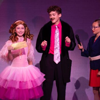 Three performers in pink musical theater scene