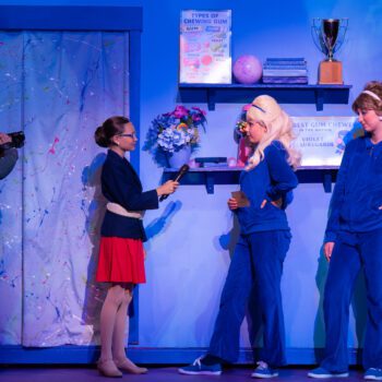 Stage interview scene with cameraman and actors