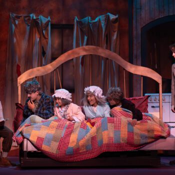 Children gathered in quilted bed on stage