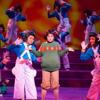 Children in colorful costumes performing stage musical