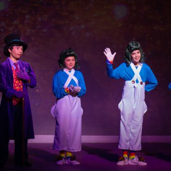 Four actors in whimsical stage costumes
