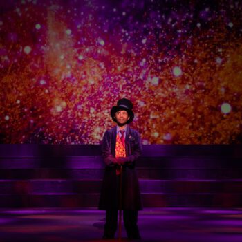 Magician in top hat on glittering stage