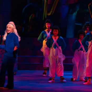 Lead performer with costumed children on stage