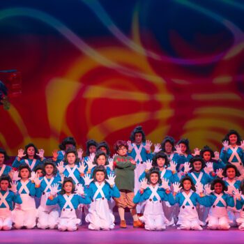 Stage ensemble in blue uniforms with candy props