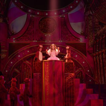 Lead actress singing on ornate red stage