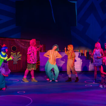 Ensemble cast in colorful costumes on stage