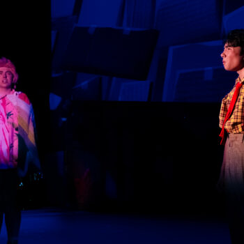 Two actors performing on stage in colorful lighting