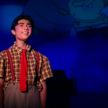 Smiling actor in plaid shirt and red tie