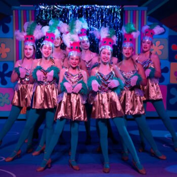 Female dancers in feathered headpieces on stage