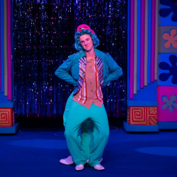 Performer in teal costume on colorful stage