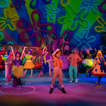 Ensemble cast in colorful costumes on stage