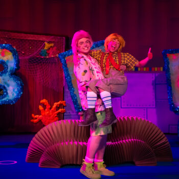 Two actors in colorful costumes on stage