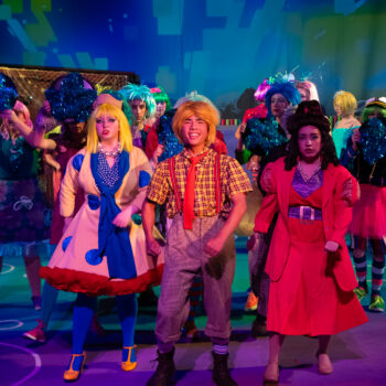 Colorful theatrical cast performing on stage